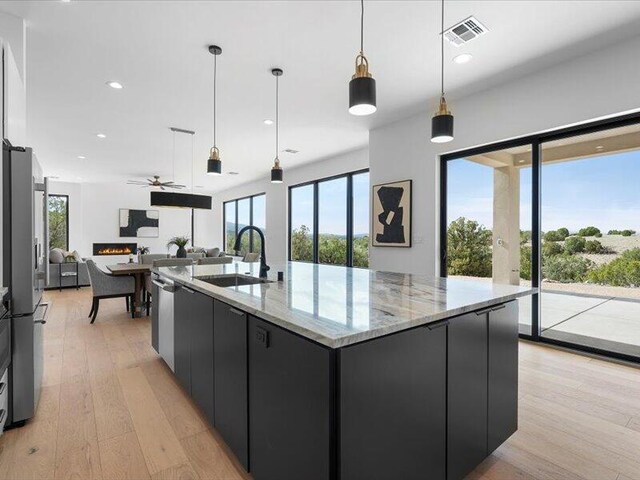 19 Anasazi Trl, Sandia Park, NM 87047 - kitchen featuring a sink, dark cabinets, decorative light fixtures, open floor plan, and visible vents