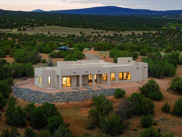 19 Anasazi Trl, Sandia Park, NM 87047 - back of house at dusk featuring a mountain view and stucco siding