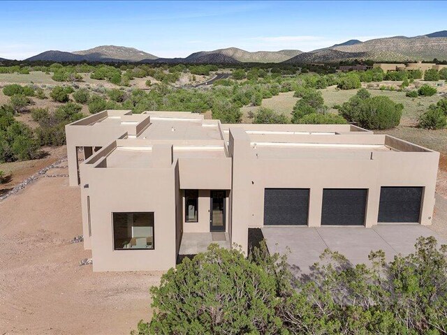 19 Anasazi Trl, Sandia Park, NM 87047 - view of front facade featuring a garage, a mountain view, stucco siding, and driveway