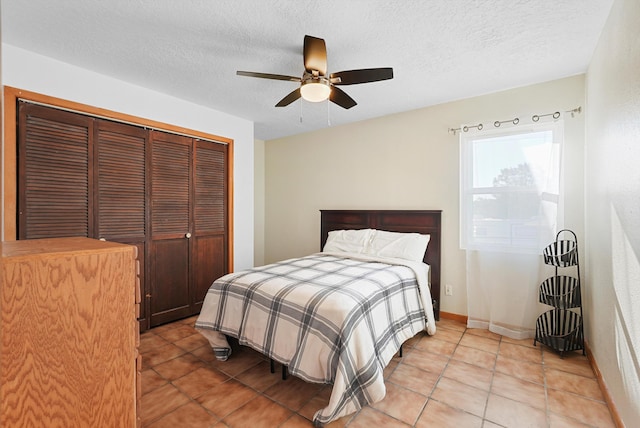 bedroom featuring a ceiling fan, a textured ceiling, baseboards, a closet, and light tile patterned flooring