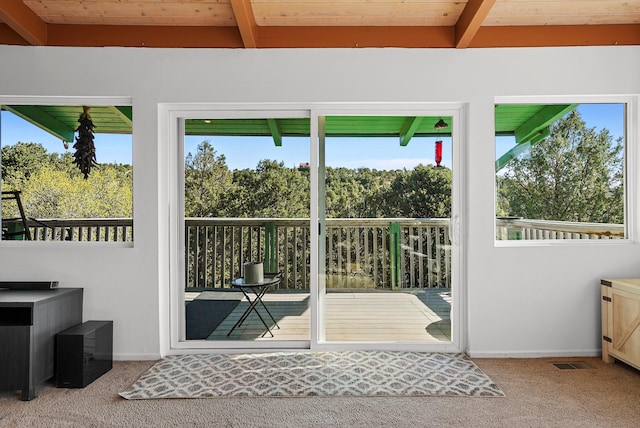 doorway to outside with beamed ceiling, a wealth of natural light, and carpet
