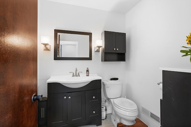 half bath featuring toilet, baseboards, visible vents, and vanity