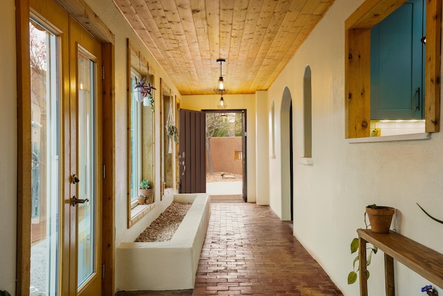 hall with wooden ceiling, brick floor, and arched walkways