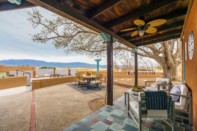 view of patio / terrace with ceiling fan, a mountain view, fence, and outdoor dining space