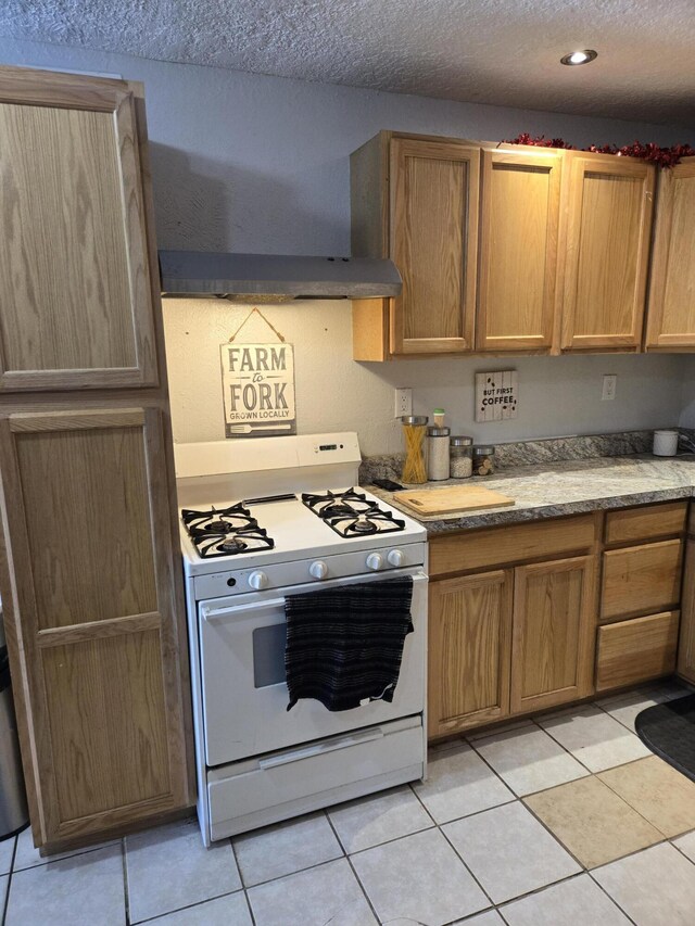 908 W Chavez Ave, Belen, NM 87002 - kitchen featuring light tile patterned floors, brown cabinetry, white gas stove, and a textured ceiling