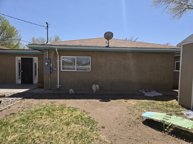 908 W Chavez Ave, Belen, NM 87002 - back of house featuring roof with shingles, stucco siding, and a yard