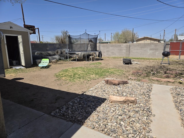 908 W Chavez Ave, Belen, NM 87002 - view of yard featuring a fenced backyard, a trampoline, a shed, and an outbuilding