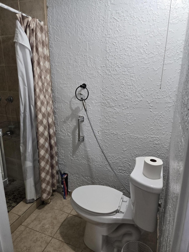 908 W Chavez Ave, Belen, NM 87002 - full bathroom featuring tile patterned flooring, a textured wall, toilet, and tiled shower