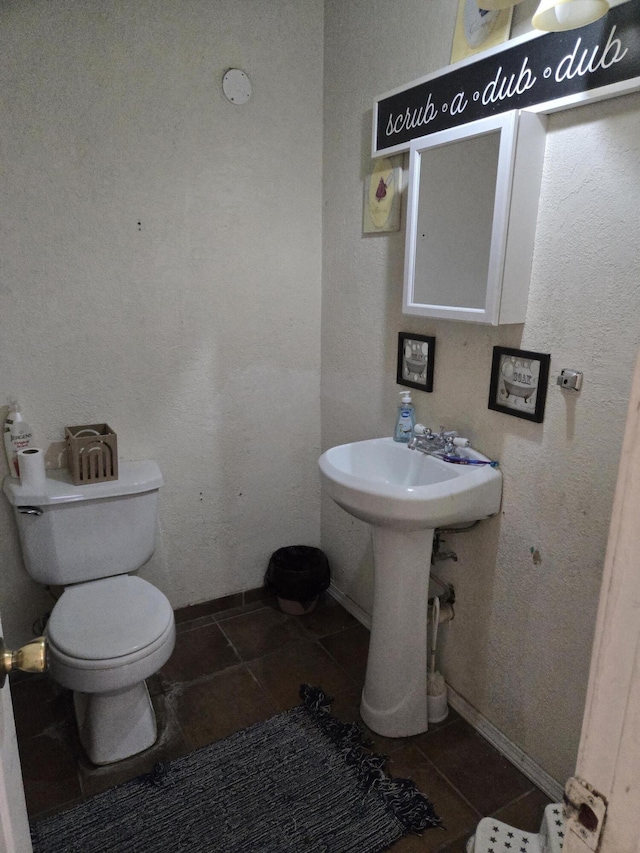 908 W Chavez Ave, Belen, NM 87002 - bathroom featuring toilet, baseboards, and tile patterned flooring
