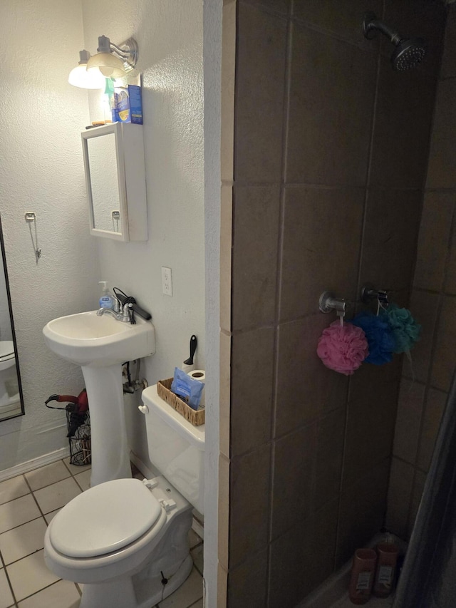 908 W Chavez Ave, Belen, NM 87002 - bathroom featuring tile patterned flooring, baseboards, toilet, and tiled shower