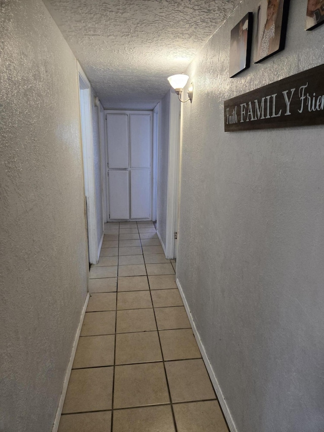 908 W Chavez Ave, Belen, NM 87002 - hall with baseboards, a textured ceiling, a textured wall, and light tile patterned floors