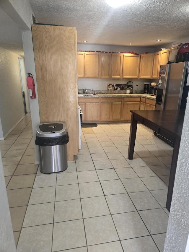 908 W Chavez Ave, Belen, NM 87002 - kitchen with freestanding refrigerator, a textured ceiling, a sink, and light tile patterned floors