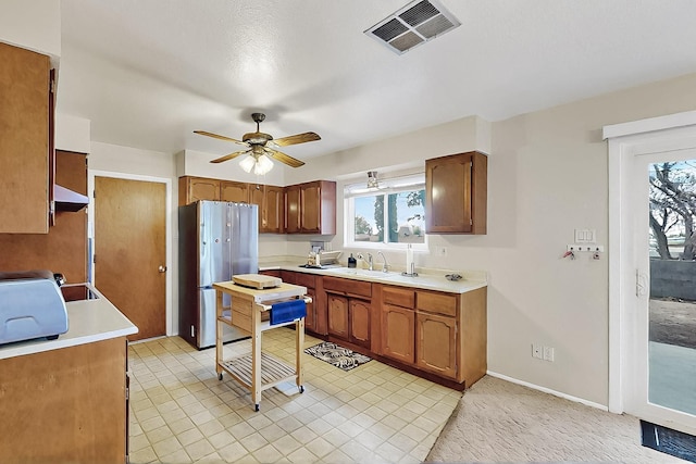 1513 Muriel St NE, Albuquerque, NM 87112 - kitchen featuring freestanding refrigerator, light countertops, ceiling fan, light tile patterned floors, and brown cabinetry
