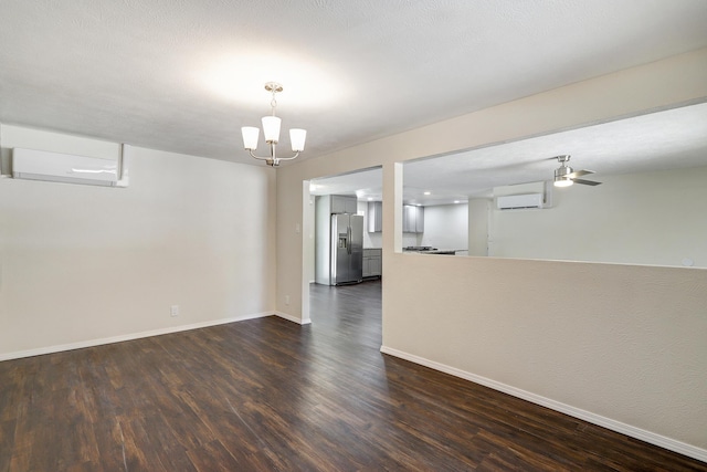 spare room featuring baseboards, a wall mounted air conditioner, dark wood-style flooring, and a notable chandelier