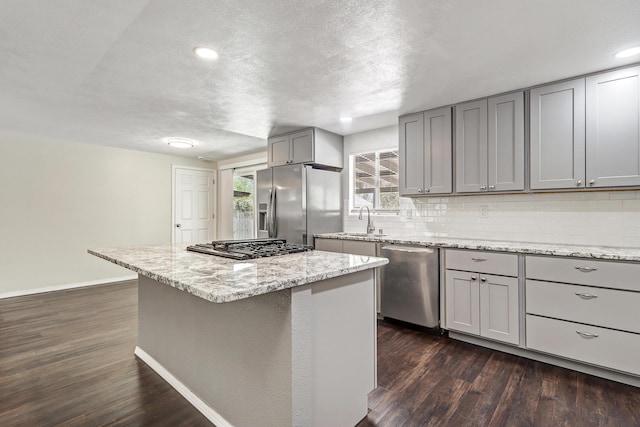 kitchen featuring dark wood-type flooring, a sink, gray cabinets, and appliances with stainless steel finishes