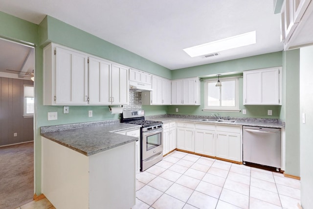 6625 Barnhart St NE, Albuquerque, NM 87109 - kitchen with under cabinet range hood, white cabinets, a sink, a skylight, and stainless steel appliances