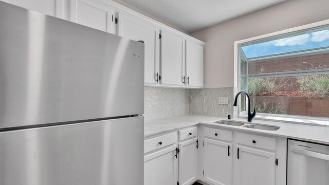 11119 Sidney Ave NE, Albuquerque, NM 87111 - kitchen with white cabinetry, tasteful backsplash, light stone counters, a sink, and stainless steel appliances