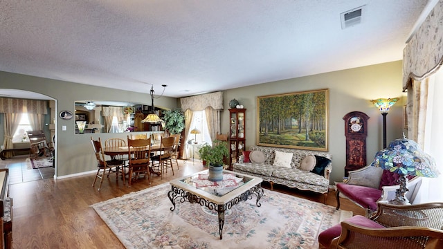 living room featuring arched walkways, a healthy amount of sunlight, visible vents, and a textured ceiling