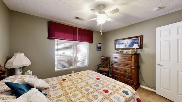 bedroom featuring a textured ceiling, ceiling fan, visible vents, and carpet floors
