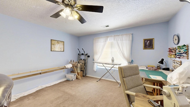 office area featuring a textured ceiling, baseboards, carpet flooring, ceiling fan, and visible vents