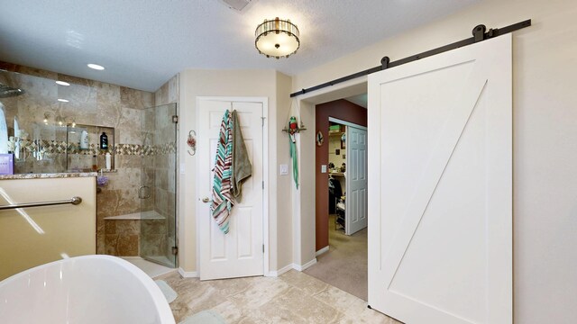 full bathroom featuring a freestanding bath, a textured ceiling, baseboards, and a shower stall