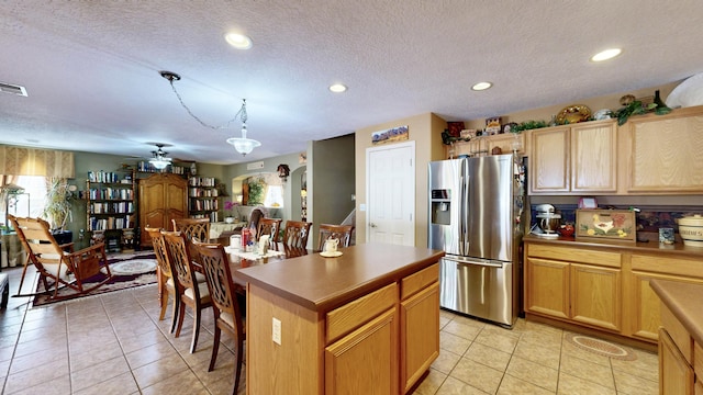kitchen featuring a kitchen island, stainless steel fridge, light tile patterned flooring, and ceiling fan