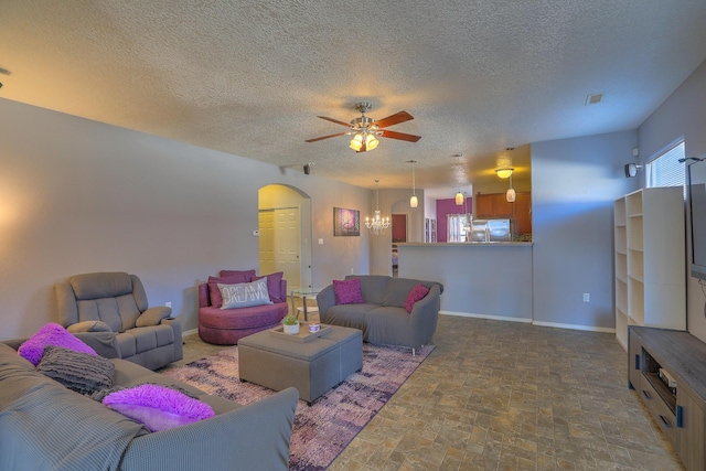 5679 Cold Creek Ave NW, Albuquerque, NM 87114 - living area featuring stone finish flooring, a textured ceiling, arched walkways, baseboards, and ceiling fan with notable chandelier