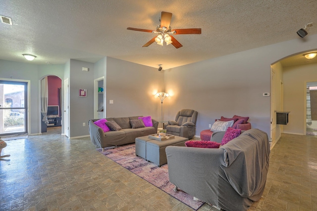 5679 Cold Creek Ave NW, Albuquerque, NM 87114 - living room with ceiling fan, arched walkways, a textured ceiling, baseboards, and visible vents