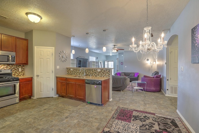 5679 Cold Creek Ave NW, Albuquerque, NM 87114 - kitchen featuring appliances with stainless steel finishes, a sink, ceiling fan with notable chandelier, a peninsula, and open floor plan