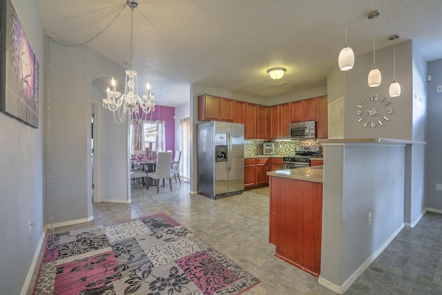 5679 Cold Creek Ave NW, Albuquerque, NM 87114 - kitchen featuring hanging light fixtures, a notable chandelier, appliances with stainless steel finishes, and decorative backsplash