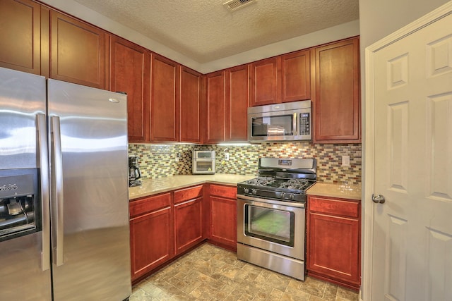 5679 Cold Creek Ave NW, Albuquerque, NM 87114 - kitchen with visible vents, decorative backsplash, light countertops, a textured ceiling, and appliances with stainless steel finishes