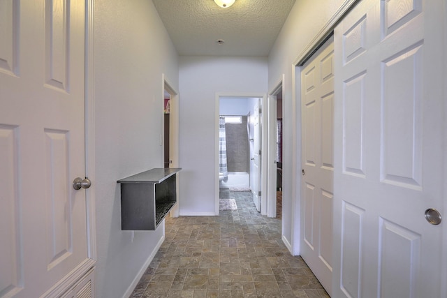 5679 Cold Creek Ave NW, Albuquerque, NM 87114 - hallway featuring baseboards, stone finish flooring, and a textured ceiling