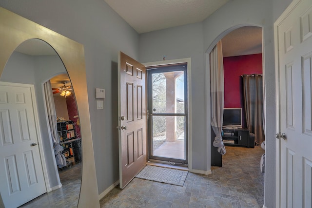 5679 Cold Creek Ave NW, Albuquerque, NM 87114 - entryway featuring baseboards, arched walkways, ceiling fan, and stone finish floor