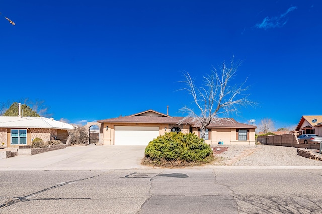 single story home featuring stucco siding, an attached garage, fence, and driveway