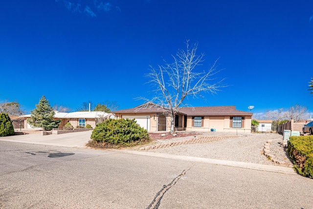 single story home with an attached garage, stucco siding, driveway, and fence