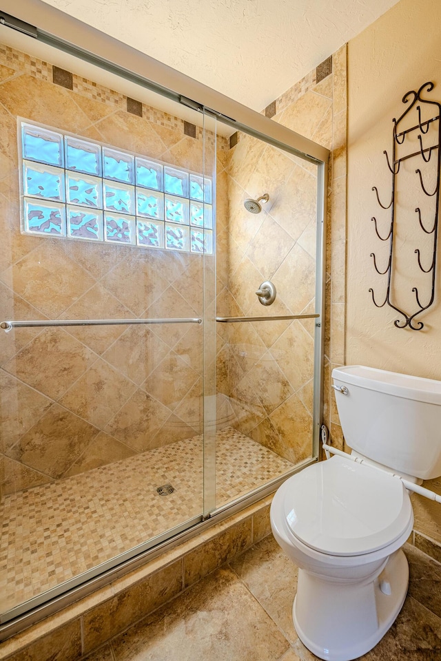 full bath with toilet, plenty of natural light, and a stall shower