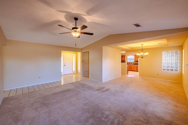 spare room featuring light colored carpet, visible vents, vaulted ceiling, baseboards, and ceiling fan with notable chandelier