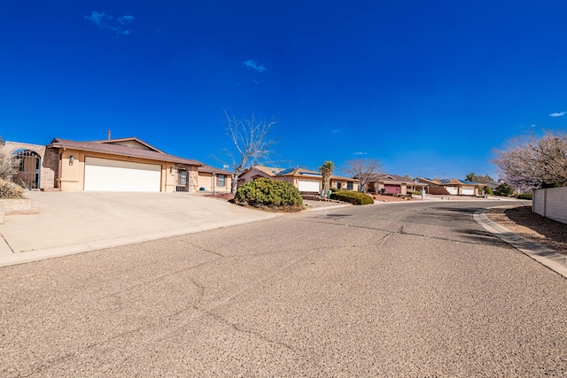 view of front facade with an attached garage, stucco siding, driveway, and a residential view