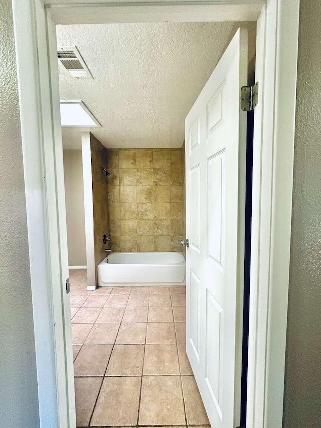 full bathroom featuring visible vents, a textured wall, a textured ceiling, tile patterned floors, and  shower combination