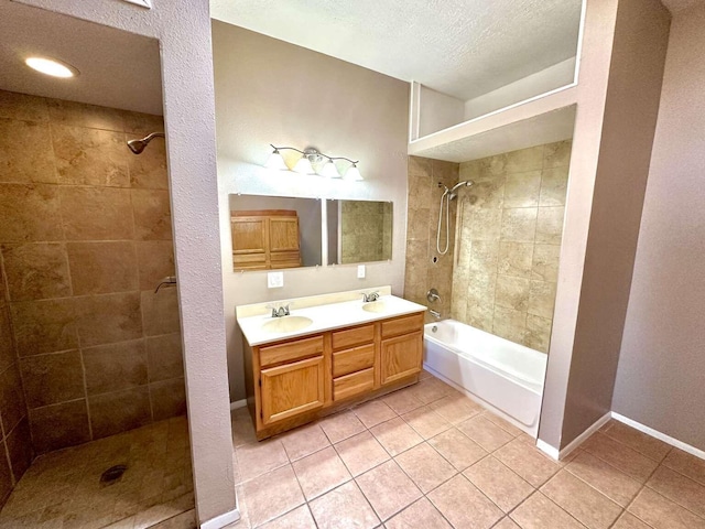 bathroom with tile patterned flooring, a sink, tiled shower / bath, and double vanity