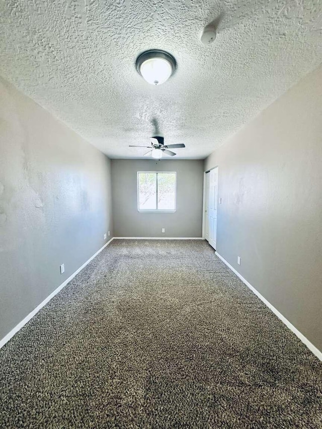 carpeted spare room with a ceiling fan, baseboards, and a textured ceiling