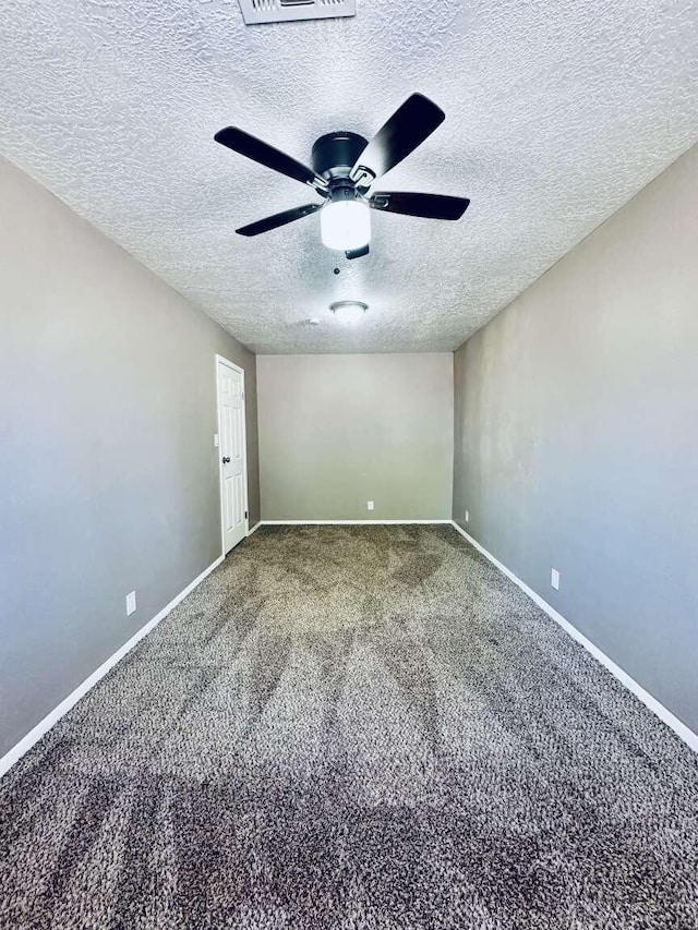 carpeted empty room with baseboards, a ceiling fan, and a textured ceiling