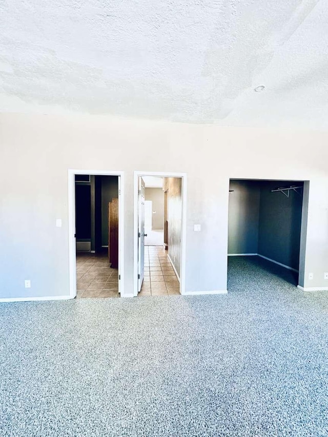 interior space featuring baseboards, tile patterned flooring, carpet, and a textured ceiling