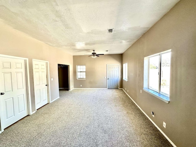 interior space with two closets, a textured ceiling, baseboards, and carpet