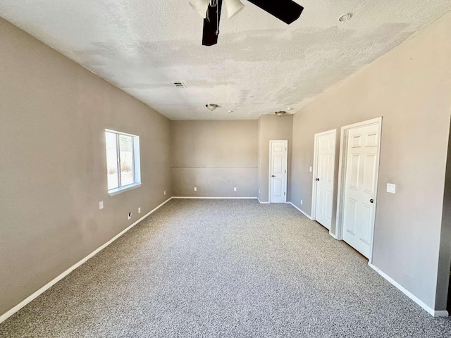 spare room with a textured ceiling, visible vents, baseboards, and carpet