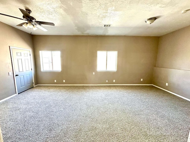 unfurnished room featuring plenty of natural light, carpet flooring, ceiling fan, and visible vents