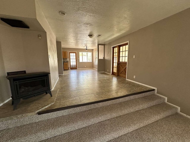 unfurnished living room with baseboards, a textured ceiling, and visible vents