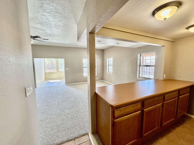 kitchen with a peninsula, baseboards, open floor plan, a textured ceiling, and a ceiling fan