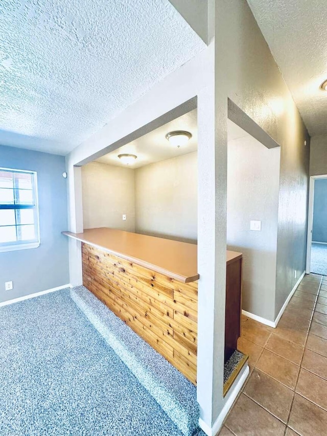 tiled spare room with baseboards and a textured ceiling