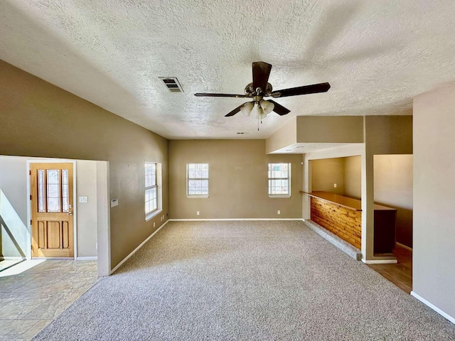 unfurnished living room with a ceiling fan, baseboards, visible vents, and a textured ceiling